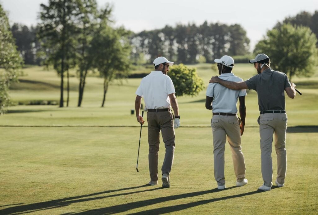 Three golf players in conversation while walking on a golf course