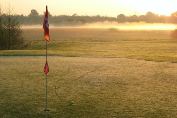 Ball near a golf hole on a golf course during sun set