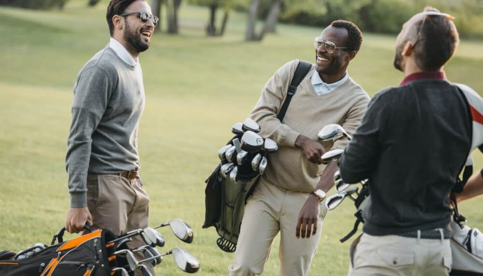 Three golf players with their golf tour bags in conversation